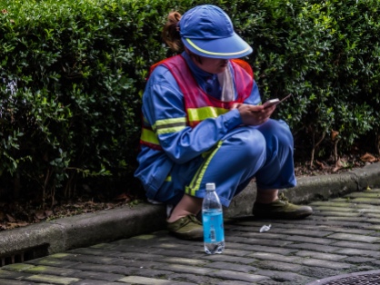 Street sweeper takes a break to check her iPhone